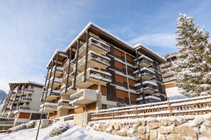A multi-story hotel with balconies, stone walls, and a snow-covered landscape.