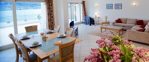 Un coin repas avec une table dressée pour quatre personnes, un canapé et une vue sur un balcon.