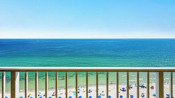 A balcony with a clear view of a beach and ocean.