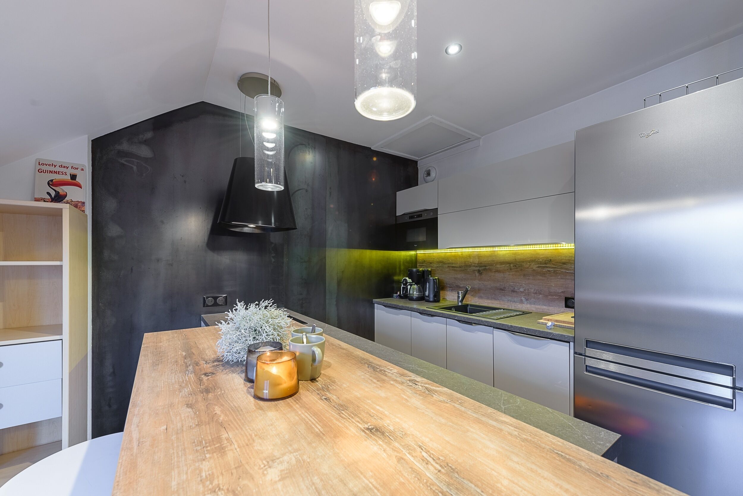 A modern kitchen with a wooden island, stainless steel appliances, and pendant lighting.