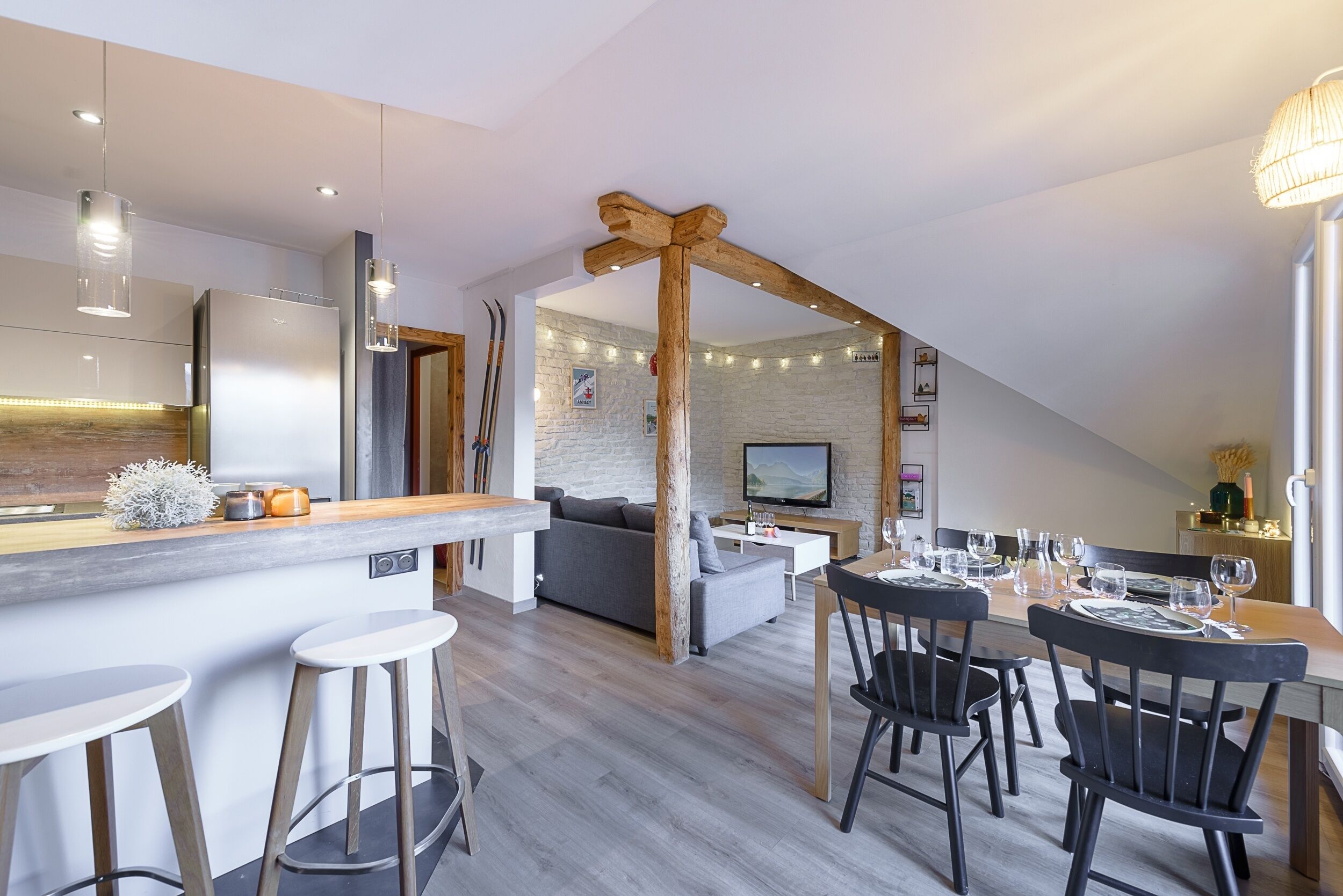 Une cuisine moderne dotée d’un coin bar, d’un espace repas avec des chaises et d’un salon avec un canapé et une télévision.
