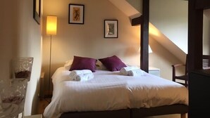 Hotelkamer met een bed, twee kussens, een nachtkastje, een lamp en ingekaderde foto's aan de muur.
