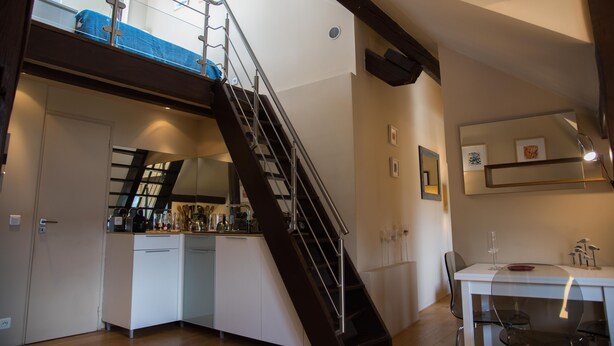 Een moderne keuken met een ingebouwde kookplaat, witte kastjes en een eethoek met een tafel en stoelen.