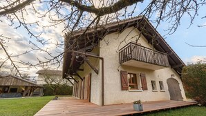 Ein Haus mit einer Holzterrasse, einem Balkon und einer großen Garagentür.