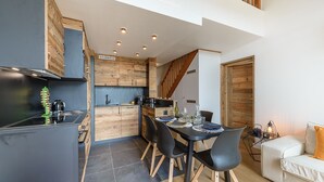 A modern kitchen with a dining area, wooden accents, and a staircase. - Le Balcon des Lys - Centre village, 4p (Veyrier-du-Lac)