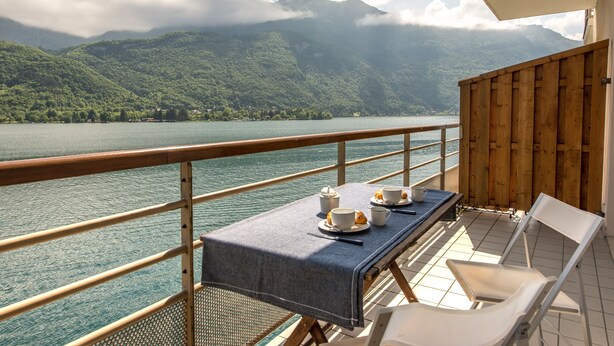 A balcony with a table set for two, overlooking a lake and mountains. - Le Studio Rivage - Surplombant le lac (Duingt)