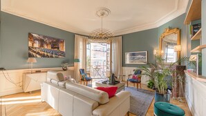 A living room with a sofa, chairs, a coffee table, and a potted plant.