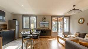 A modern kitchen with a dining area, a sofa, and a TV.