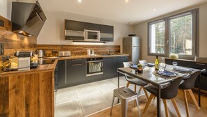 A modern kitchen with a wooden island, stainless steel appliances, and a large window providing natural light.