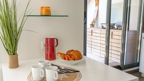 Ein Frühstückstisch mit einer weißen Tischdecke, einer roten Tasse, einer Schüssel Croissants und einer Topfpflanze.