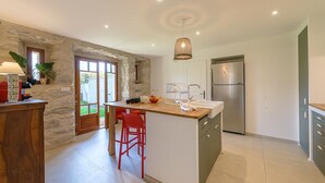 A modern kitchen with a central island, a built-in sink, and a stainless steel refrigerator. - La Grande Mélodie - Maison familiale avec jardin (Saint-Jorioz)