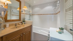 A modern bathroom with two sinks, a shower, and a bathtub.