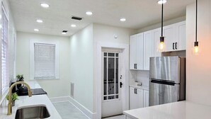 A modern kitchen with white cabinetry, stainless steel appliances, and pendant lighting. - Bright & Modern Prime Location (Jacksonville)