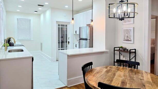A modern kitchen with white cabinetry, a central island, and pendant lighting. - Bright & Modern Prime Location (Jacksonville)