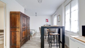 A modern kitchen with a wooden cabinet, a dining table with stools, and a window with curtains.
