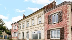A two-story building with a classic facade, featuring a mix of brick and plaster, and a row of windows with shutters.