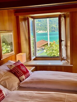 A bedroom with a large window offering a view of a coastal landscape.