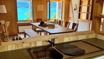 Fully equipped alpine kitchen with sink, dishwasher, and direct view into the dining area and Lake Brienz