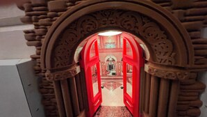 Un modelo de edificio con un arco rojo que da a una habitación con candelabro.