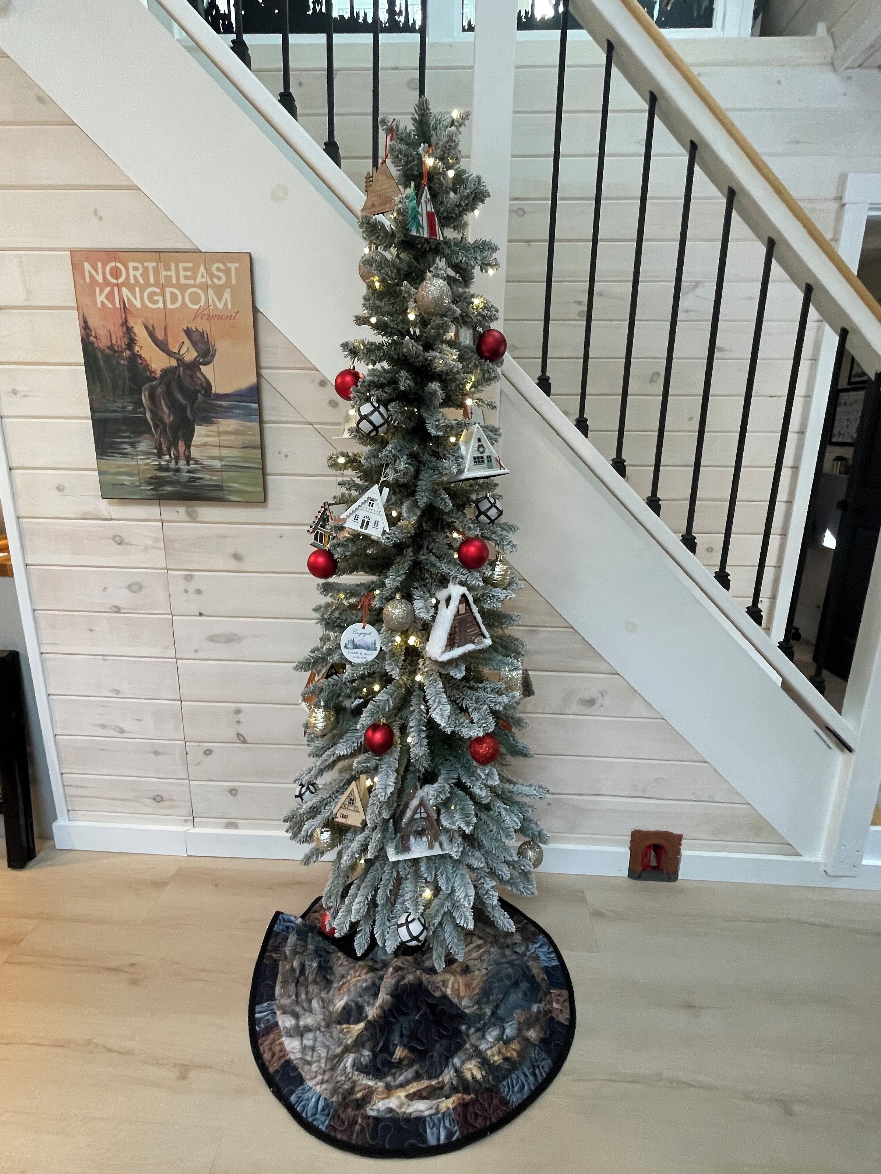 A Christmas tree with ornaments and a snowflake decoration on a wooden floor.