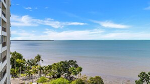 Een hotel aan het strand met uitzicht op de oceaan, palmbomen en een heldere lucht.