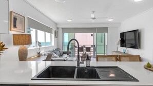 Een moderne keuken met een groot eiland, een inbouwspoelbak en een eetgedeelte met uitzicht buiten.