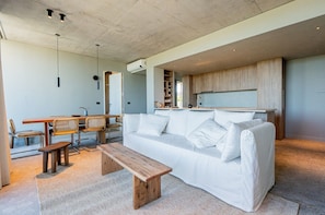 Una sala de estar moderna con un sofá, un banco de madera, una mesa de comedor y sillas.