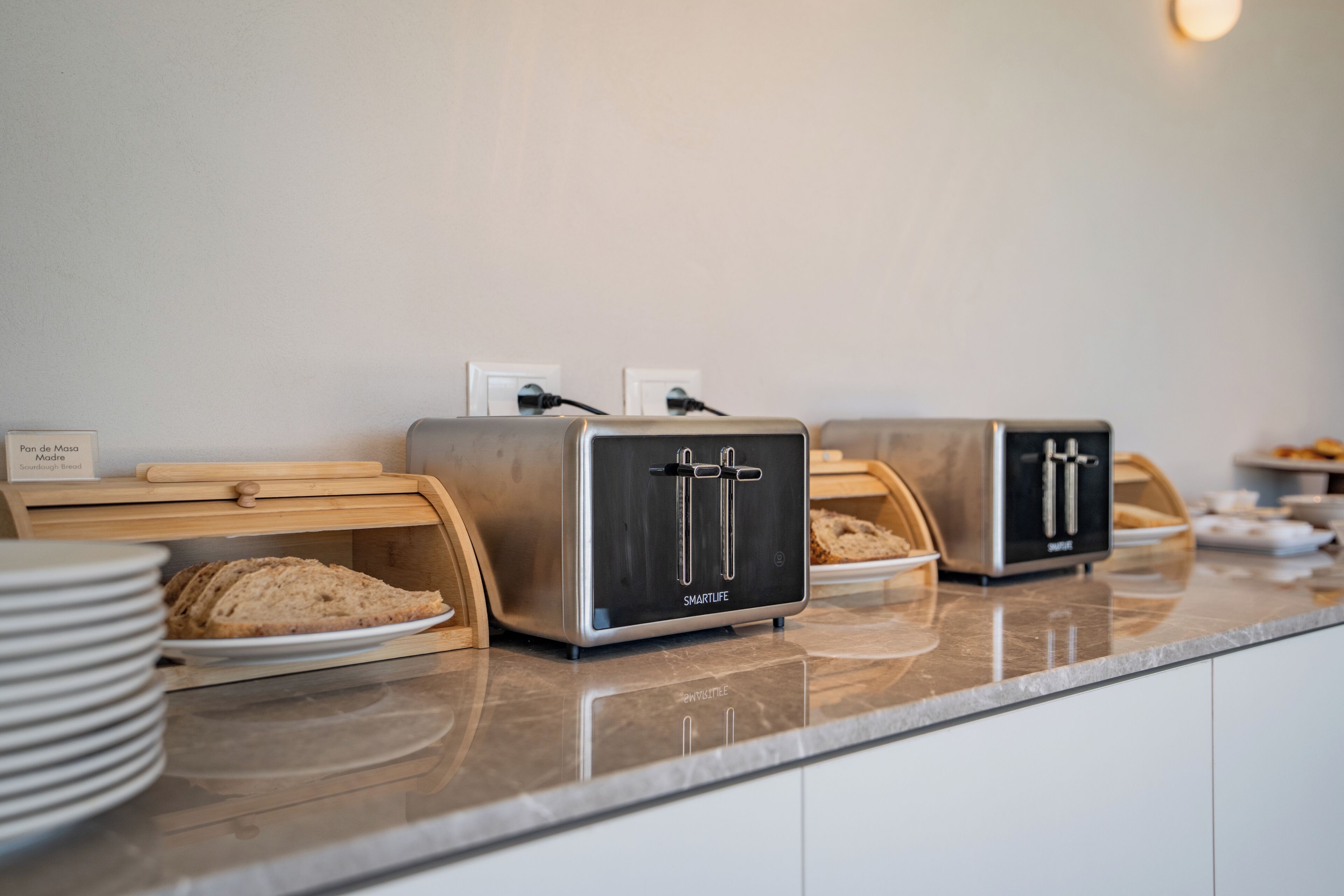 A kitchen counter with two bread toasters and a sign indicating 'Bread Freshly Baked.'