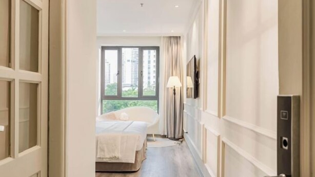 A hotel room with a bed, a window with curtains, a lamp, and a door. - Keypad Hotel - Nhân Hòa (Hanoi)