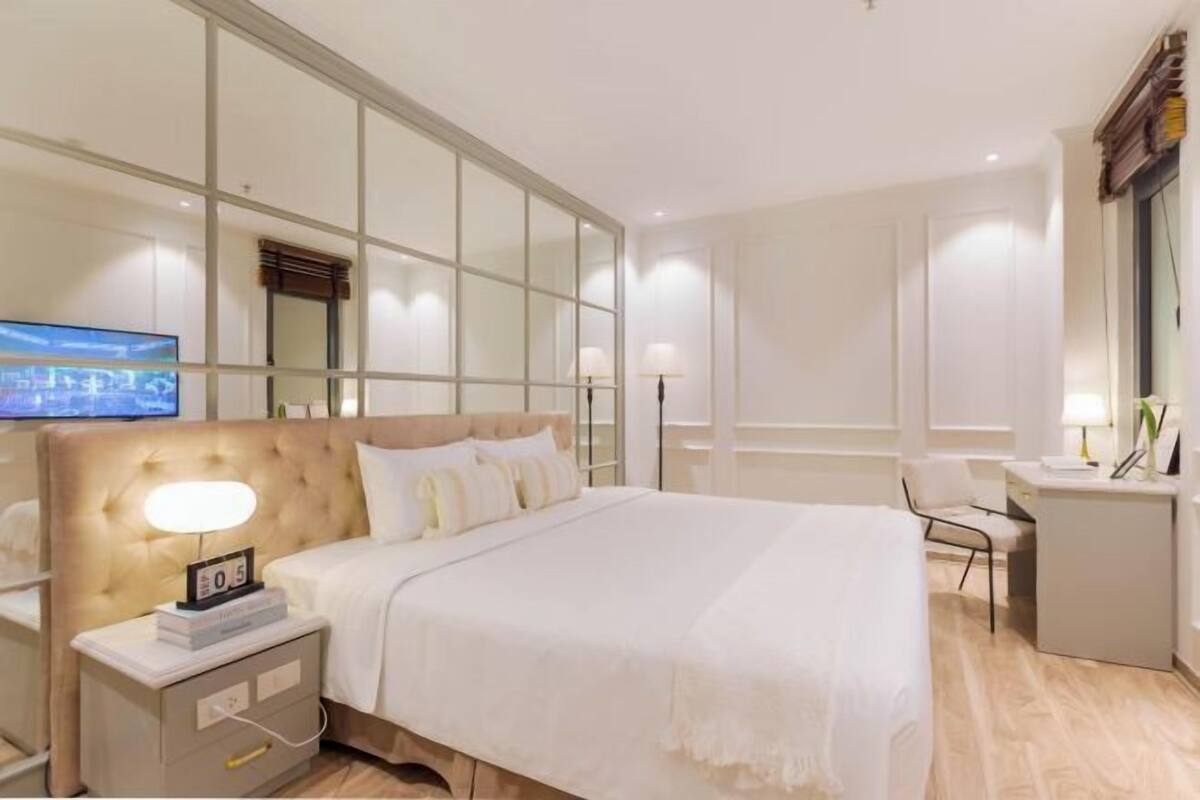 Habitación de hotel con una cama grande, una mesita de noche con lámpara, un televisor y un escritorio con silla.