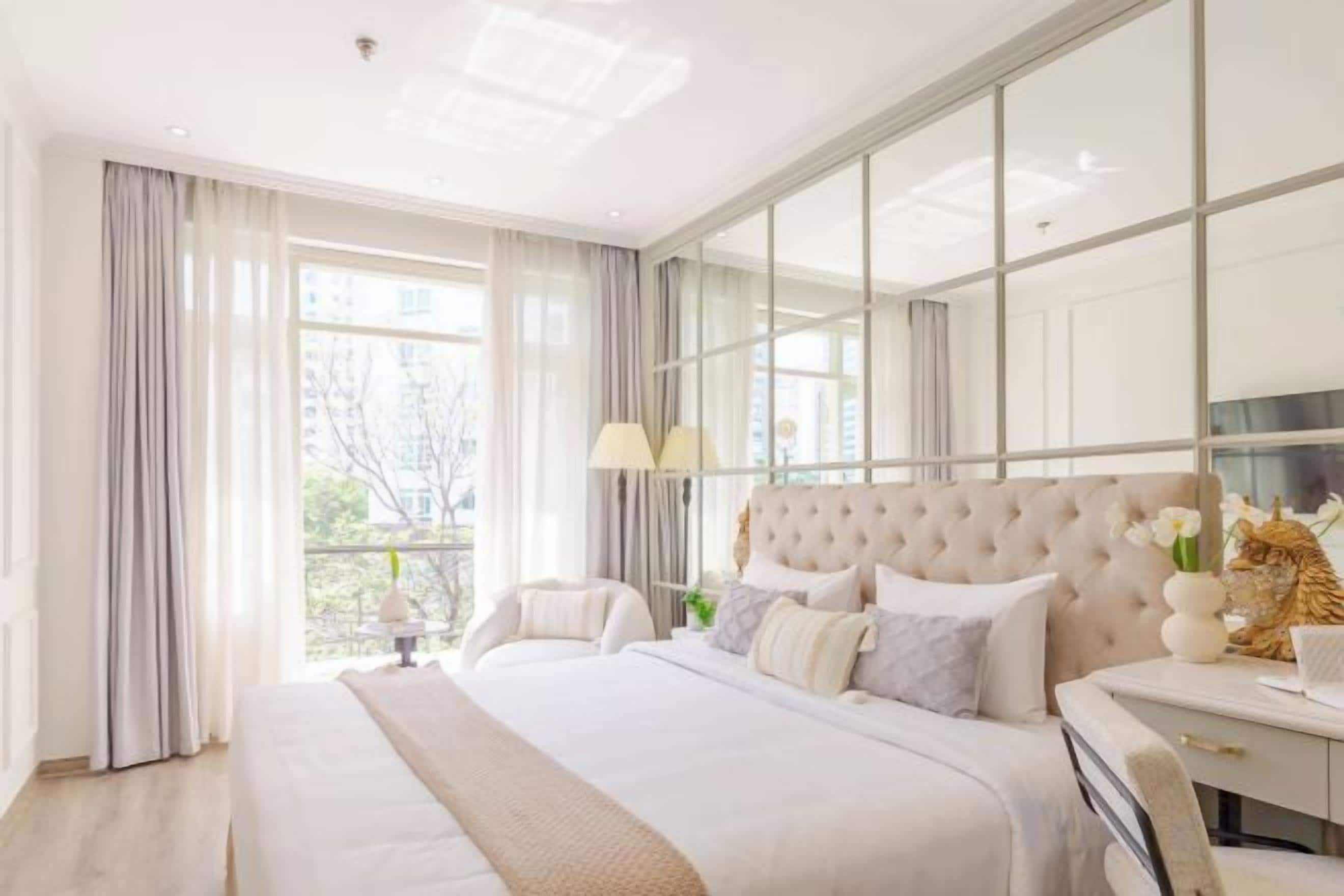 A modern bedroom with a large bed, bedside tables, and a view through a large window.