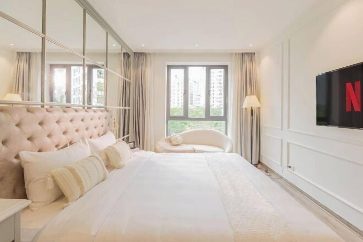 Habitación de hotel moderna con una cama grande, televisión y vista a la ciudad.
