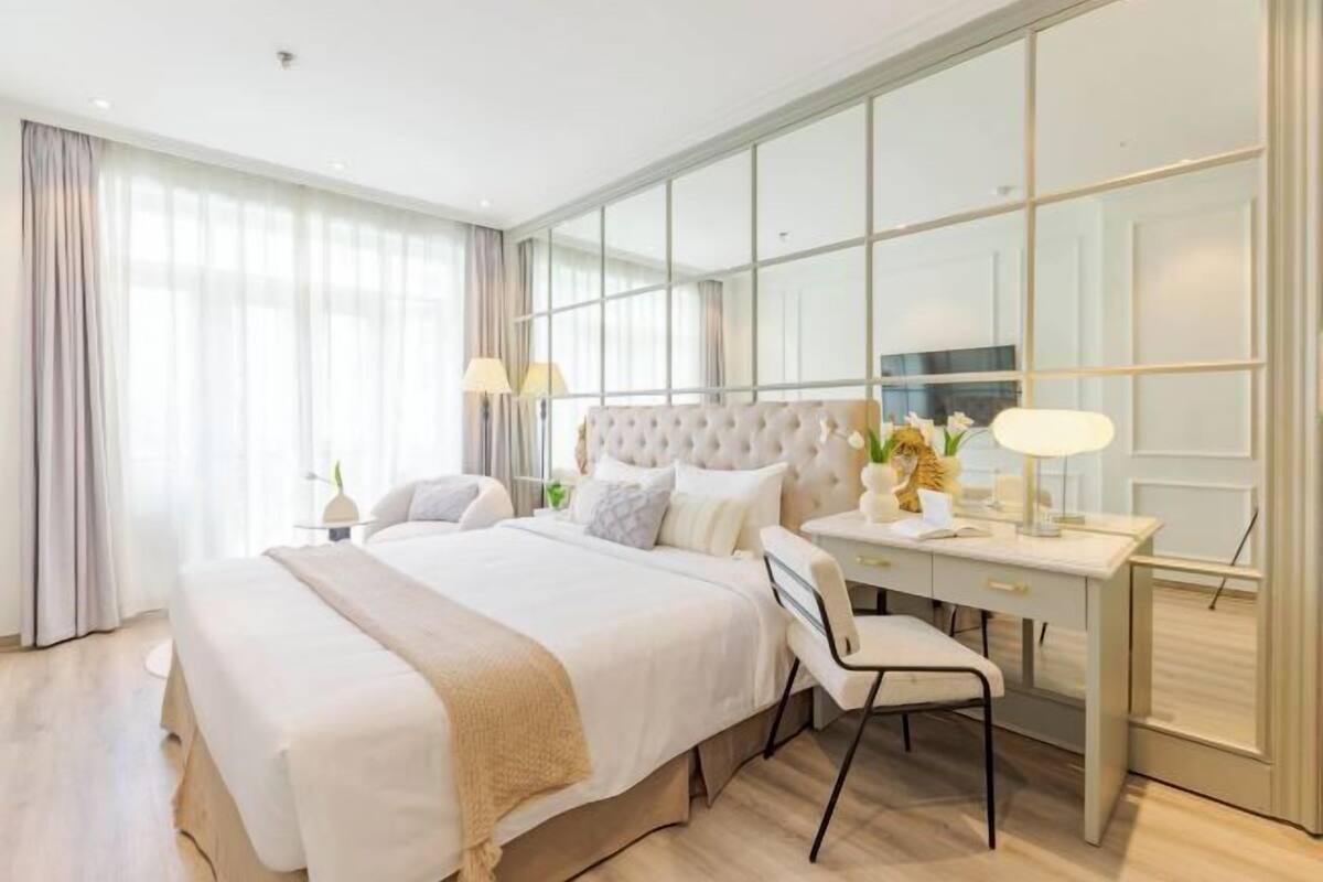 Una habitación de hotel moderna con una cama grande, un escritorio y un espejo.