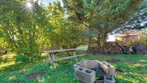 A picnic table and a fire pit in a grassy area with trees. - Fish & Hike! Home Base for Kachemak Bay Adventures (Homer)