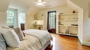 A bedroom with a large bed, a ceiling fan, wooden flooring, and built-in shelving with books and decorative items. - Home 2 Mi to Shenandoah Nat'l Park & Skyline Drive (Front Royal)