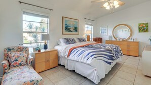 Une chambre à coucher comprenant un lit, une chaise, une commode, un ventilateur de plafond et une fenêtre avec des stores.