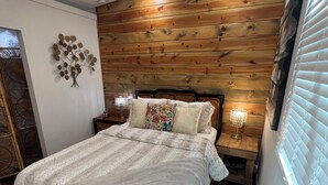A bedroom with a wooden headboard, a bed with a white duvet, two bedside tables with lamps, and a ceiling fan. - Quiet retreat near Anthony’s chapel & Garvan Gardens (Hot Springs)