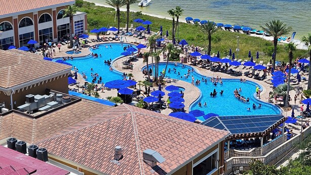 A resort with multiple swimming pools, beach access, and a large building with a tiled roof.
