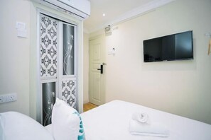 A hotel room with a bed, a TV mounted on the wall, a wardrobe with patterned doors, and a door leading to another room. - Swing & Pillows - Sungei Wang Bukit Bintang (Kuala Lumpur)