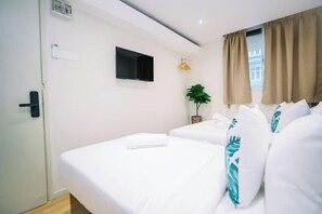 A hotel room with two beds, a TV mounted on the wall, a window with curtains, and a plant on the windowsill. - Swing & Pillows - Sungei Wang Bukit Bintang (Kuala Lumpur)