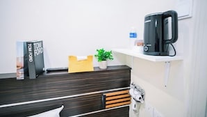 A reception desk with a dark wood finish, a plant, a water bottle, a coffee maker, and a book titled 'TOM FORD'.
