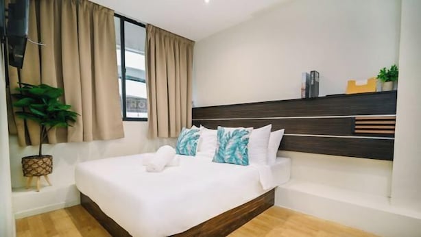 A modern bedroom with a large bed, wooden headboard, and a view of the city.