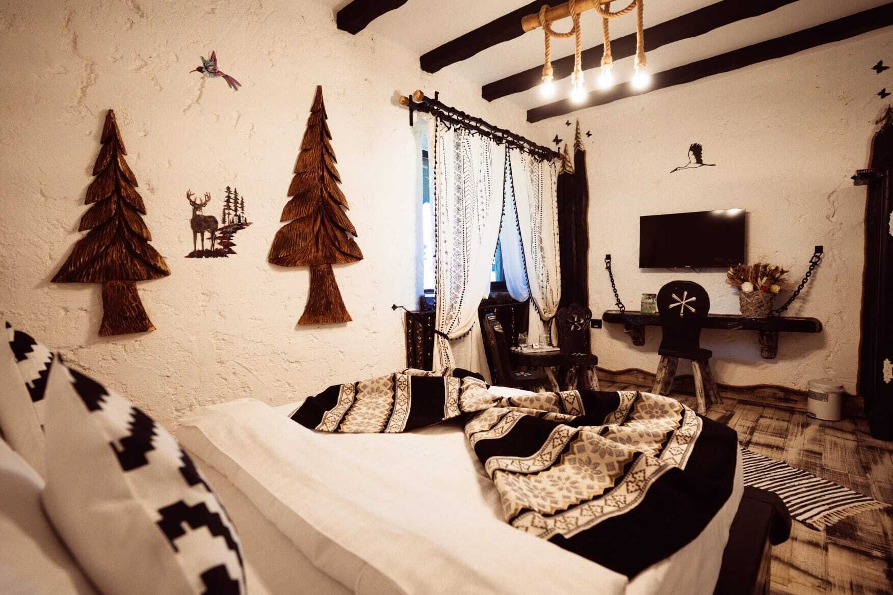 Una habitación acogedora con una cama, un sillón, un televisor y adornos en la pared, incluyendo un ciervo y árboles.