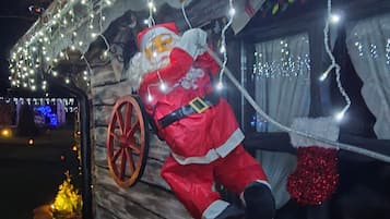 A decorated outdoor area with a large Santa Claus figure, stone paving, and string lights.
