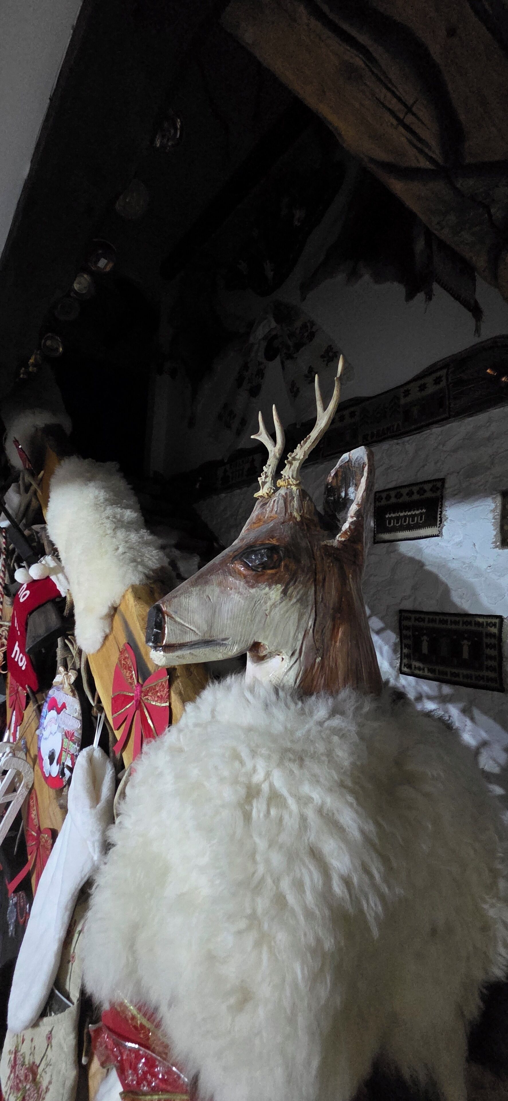 Una habitación con una gran escultura de cabeza de ciervo, una chimenea y varias decoraciones, incluyendo un muñeco de Santa Claus y una placa de perro.