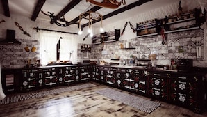 A rustic kitchen with exposed beams, a wooden ceiling, and a tiled backsplash. - Agi Traditional  (Bran)