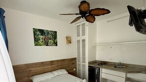 A compact bedroom with a bed, a desk, and a ceiling fan. - Traveler SOLO (Playa del Carmen)