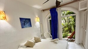 A bedroom with a bed, a ceiling fan, a painting, and a view of the outdoors. - Traveler SOLO (Playa del Carmen)