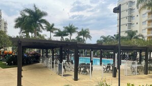 A pool area with a covered seating area, lounge chairs, and a pool.