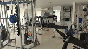Uma academia com diversos equipamentos de exercícios, incluindo aparelhos de musculação, esteiras e uma barra para barra fixa.